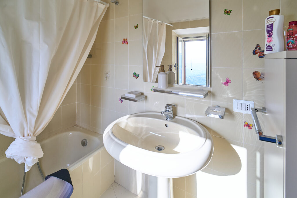 Bagno con vasca, lavabo e finestra, con piastrelle decorate